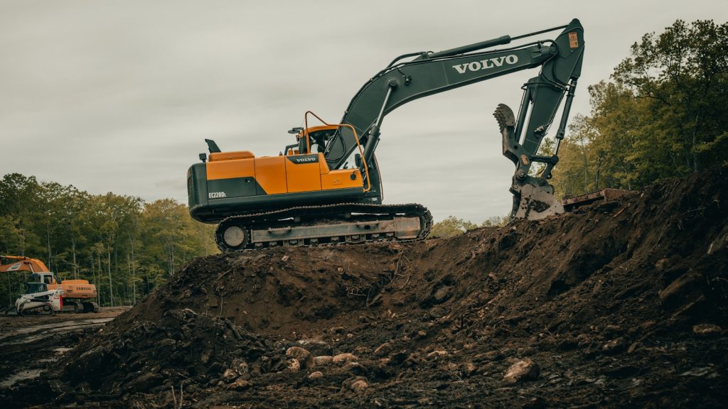 orange and white excavator on brown ground during daytime